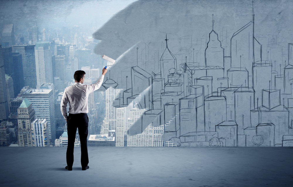 A businessman in elegant suit holding a paint roller in his hand and painting drawn city landscape over urban skyscrapers concept-1