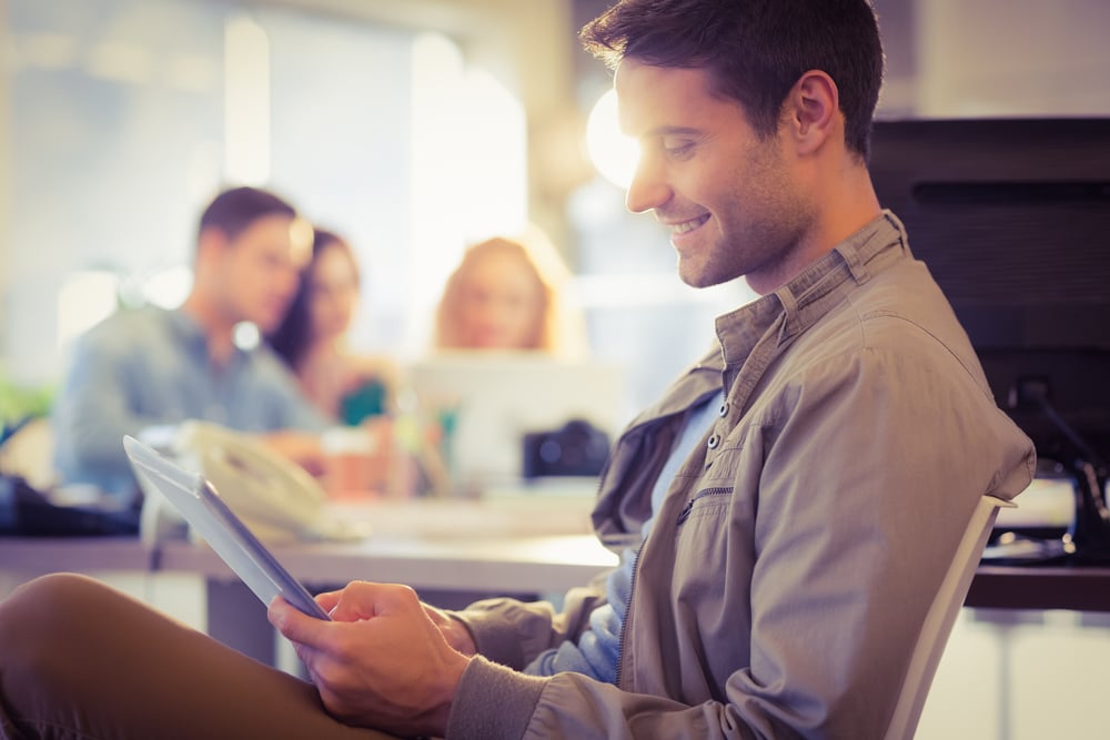 Smiling young man using digital tablet in the office-1